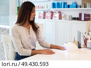 Woman using manicured nails in UV lamp. Small nail art and manicure business. Hands of woman in a wellnes salon. Стоковое фото, агентство Ingram Publishing / Фотобанк Лори