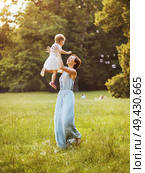Delighted young mother tossing her lovely child. Стоковое фото, агентство Ingram Publishing / Фотобанк Лори