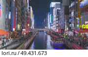 Osaka, Japan - Sep 22 2024, 4k, Panoramic view of Dotonbori river with a ship with tourists, a lot of people on embankment, there are a lot of advertising and illuminations on buildings, Osaka, Japan. Редакционное видео, видеограф Сергей Богомяко / Фотобанк Лори