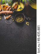 Mug of healthy turmeric milk drink with ingredients: fresh turmeric roots , spices and honey on dark background, top view.  Hot winter beverage. Immune boosting remedy , detox and dieting concept. Стоковое фото, агентство Ingram Publishing / Фотобанк Лори