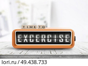 Time to excercise message on an alarm clock in a bright living room on a wooden table. Стоковое фото, агентство Ingram Publishing / Фотобанк Лори