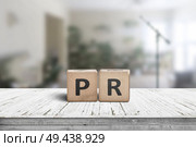 PR sign on a worn table in a bright room with green plants and a microphone. Стоковое фото, агентство Ingram Publishing / Фотобанк Лори