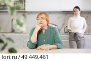 Elderly sad woman sits at table in kitchen and listens to insults.Concept stream of abuse. Стоковое фото, фотограф Яков Филимонов / Фотобанк Лори