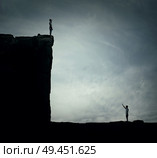 Conceptual image with two lost persons standing on a cliff at different hights, trying to find each other. Parallel world, alternate reality, multiverse fiction theory and relativity. Human life cycle, highs and lows. Стоковое фото, агентство Ingram Publishing / Фотобанк Лори