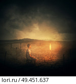 Surrealist concept as a man, sitting on a chair in the middle of a desert, looking at a single burning matchstick through a set of another extinguished, burnt matches. Стоковое фото, агентство Ingram Publishing / Фотобанк Лори