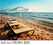 Beautiful sandy beach with sunbeds and sea umbrellas facing the sunrise in the morning. Summer background in Nessebar, Bulgaria. Стоковое фото, агентство Ingram Publishing / Фотобанк Лори