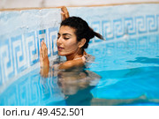 Beautiful Arab woman relaxing in swimming pool with eyes closed. Girl with healthy tanned skin and wet hair enjoying Summer Sun.. Beautiful Arab woman relaxing in swimming pool. . Стоковое фото, агентство Ingram Publishing / Фотобанк Лори