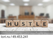 Hustle sign with text on a worn desk in a courtroom with bright lights. Стоковое фото, агентство Ingram Publishing / Фотобанк Лори