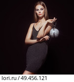 Beautiful young woman in Little black dress. Girl posing on a black background. Blonde girl with long healthy and shiny hair. Care and Beauty. Fashion photo. Glamour lady with a handbag of shiny gems. Стоковое фото, агентство Ingram Publishing / Фотобанк Лори