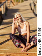 Woman enjoying the sunset on a beautiful beach in Cadiz, Andalusia, Spain. Young female smiling sitting on wooden bridge.. Smiling woman enjoying the sunset on a beautiful beach. Стоковое фото, агентство Ingram Publishing / Фотобанк Лори