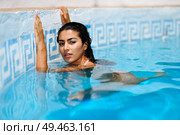 Happy young woman relaxing in swimming pool. Beautiful girl with healthy tanned skin and wet hair enjoying Summer Sun at pool edge.. Beautiful Arab woman relaxing in swimming pool. . Стоковое фото, агентство Ingram Publishing / Фотобанк Лори