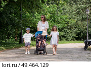 A family with three children. A mother with many children and toddlers in a summer park. Children are walking in the fresh air. Having many children and family values. Стоковое фото, фотограф Photojuli / Фотобанк Лори