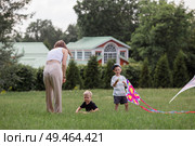 A family with three children. A mother with many children and toddlers in a summer park. Children are walking and flying a kite. Large families, family values, and leisure time with children. Стоковое фото, фотограф Photojuli / Фотобанк Лори