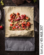 Rhubarb and strawberries strudel pie preparation. Dough sheet with sliced ingredients sugar and starch powder on rustic kitchen table, top view. Seasonal baking. Organic food. Step by step. Стоковое фото, агентство Ingram Publishing / Фотобанк Лори