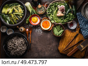 Asian food background. Tasty vegetarian ingredients. Various green vegetables,  soba noodles - buckwheat noodles, flavor salt and chili hot sauce on rustic kitchen table background with chopsticks. Стоковое фото, агентство Ingram Publishing / Фотобанк Лори