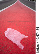 Concept of pollution by plastic littering on red road. Стоковое фото, агентство Ingram Publishing / Фотобанк Лори