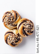 Three freshly baked chocolate swirl buns topped with chopped almonds, arranged on a white background, showcasing a delicious combination of texture, sweetness, and detail. Стоковое AI-изображение, AI-художник Катерина Бондарец / Фотобанк Лори
