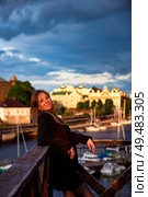 Woman Enjoying a Sunset by the Waterfront in a Charming Coastal Town. Стоковое фото, фотограф Aleksandr Golubev / Фотобанк Лори