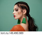 Brunette girl with perfect makeup. Beautiful model woman with curly hairstyle. Care and beauty hair products. Lady with braided hair. Model with jewelry. Turquoise background. Стоковое фото, агентство Ingram Publishing / Фотобанк Лори