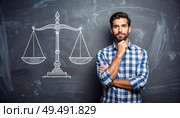 Man standing in front of chalk-drawn justice scales representing fairness, legal balance, law education, or moral decision-making. Стоковое AI-изображение, AI-художник Igor Tichonow / Фотобанк Лори