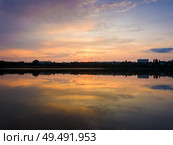 Colorful sunset clouds symmetric reflected on the lake surface. Idyllic summer evening, natural scene near a countryside pond with calm water. Стоковое фото, агентство Ingram Publishing / Фотобанк Лори
