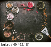 Homemade chocolate factory background. Various chocolate topping , melted chocolate in bowls , spatula, nuts, marshmallow, nuts, liquorice, caramel and candy on dark table. Top view. Copy space. Стоковое фото, агентство Ingram Publishing / Фотобанк Лори