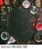 Homemade chocolate factory background. Preparation of chocolate with various topping: candy, marshmallow, nuts, liquorice, caramel, dried fruits, and spices. Melted chocolate in bowls with spatula. Стоковое фото, агентство Ingram Publishing / Фотобанк Лори
