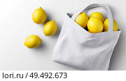 Fresh lemons tucked inside a reusable tote bag for grocery shopping. Свежие лимоны в многоразовой сумке для покупок. Стоковое AI-изображение, AI-художник Katsiaryna Repich / Фотобанк Лори