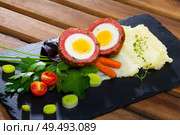 Dish scotch egg with tomatoes, mashed potatoes and greens, traditional Scottish cuisine. Стоковое фото, фотограф Яков Филимонов / Фотобанк Лори