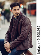 Thoughtful young man sitting on an urban bench. Attractive guy with modern hairstyle with lost look in the street.. Thoughtful young man sitting on an urban bench. Стоковое фото, агентство Ingram Publishing / Фотобанк Лори