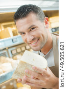 Shop assistant holding chunk of cheese. Стоковое фото, агентство Ingram Publishing / Фотобанк Лори
