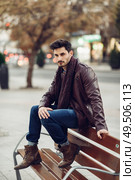 Thoughtful young man sitting on an urban bench. Attractive guy with modern hairstyle with lost look in the street.. Thoughtful young man sitting on an urban bench. Стоковое фото, агентство Ingram Publishing / Фотобанк Лори