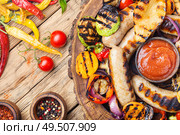 Grilled sausages and vegetables with sauce ketchup on a wooden table.Autumn food. Fried sausages with sauces. Стоковое фото, агентство Ingram Publishing / Фотобанк Лори