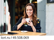 Beautiful woman drinking coffee in an urban cafe bar. Young female sitting at table at an outside terrace. Girl with california highlights hairstyle.. Middle-aged woman drinking coffee in an urban cafe bar. Стоковое фото, агентство Ingram Publishing / Фотобанк Лори