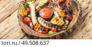 Grilled sausages and vegetables with sauce ketchup on wooden tray.Bbq food. Grilled sausages with vegetables. Стоковое фото, агентство Ingram Publishing / Фотобанк Лори