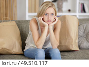 grumpy woman sat on sofa with shopping bags around her. Стоковое фото, агентство Ingram Publishing / Фотобанк Лори