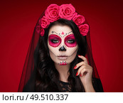 Portrait of a woman with sugar skull makeup over red background. Halloween costume and make-up. Portrait of Calavera Catrina. Стоковое фото, агентство Ingram Publishing / Фотобанк Лори