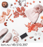 Autumn beauty feminine arrangement on white background with knit hat with pom pom,pumpkin. sneakers, smartphone with mock up , fall leaves, cosmetics and mug with hot chocolate. Top view. Flat lay. Стоковое фото, агентство Ingram Publishing / Фотобанк Лори