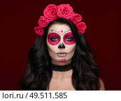 Portrait of a woman with sugar skull makeup over red background. Halloween costume and make-up. Portrait of Calavera Catrina. Стоковое фото, агентство Ingram Publishing / Фотобанк Лори