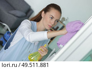 female janitor cleaning refrigerator door with rag. Стоковое фото, агентство Ingram Publishing / Фотобанк Лори