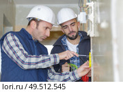 two workmen screwing electric terminal to wall. Стоковое фото, агентство Ingram Publishing / Фотобанк Лори