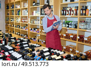 joyful male seller in uniform holding clipboard in wine shop. Стоковое фото, агентство Ingram Publishing / Фотобанк Лори