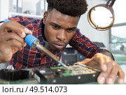 man solders a chip in a workshop. Стоковое фото, агентство Ingram Publishing / Фотобанк Лори