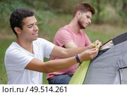 two young men erecting tent. Стоковое фото, агентство Ingram Publishing / Фотобанк Лори