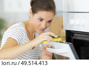 young woman washes a microwave. Стоковое фото, агентство Ingram Publishing / Фотобанк Лори