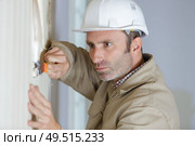 craftsman at home renovation scratches old wallpaper from wall. Стоковое фото, агентство Ingram Publishing / Фотобанк Лори