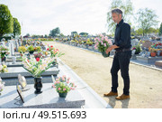 Man by graveside holding pot of flowers. Стоковое фото, агентство Ingram Publishing / Фотобанк Лори