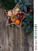 Christmas flat lay scene with tangerines and fir tree decotations, copy space on wooden background, Christmas celebration and gift giving concept. Christmas flat lay scene with golden decorations. Стоковое фото, агентство Ingram Publishing / Фотобанк Лори