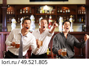 Three men with beer rejoice the victory of their favorite team in the pub. Стоковое фото, агентство Ingram Publishing / Фотобанк Лори