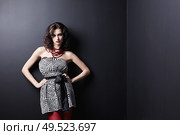 Attractive young woman in a dress on a background of black walls. Стоковое фото, агентство Ingram Publishing / Фотобанк Лори